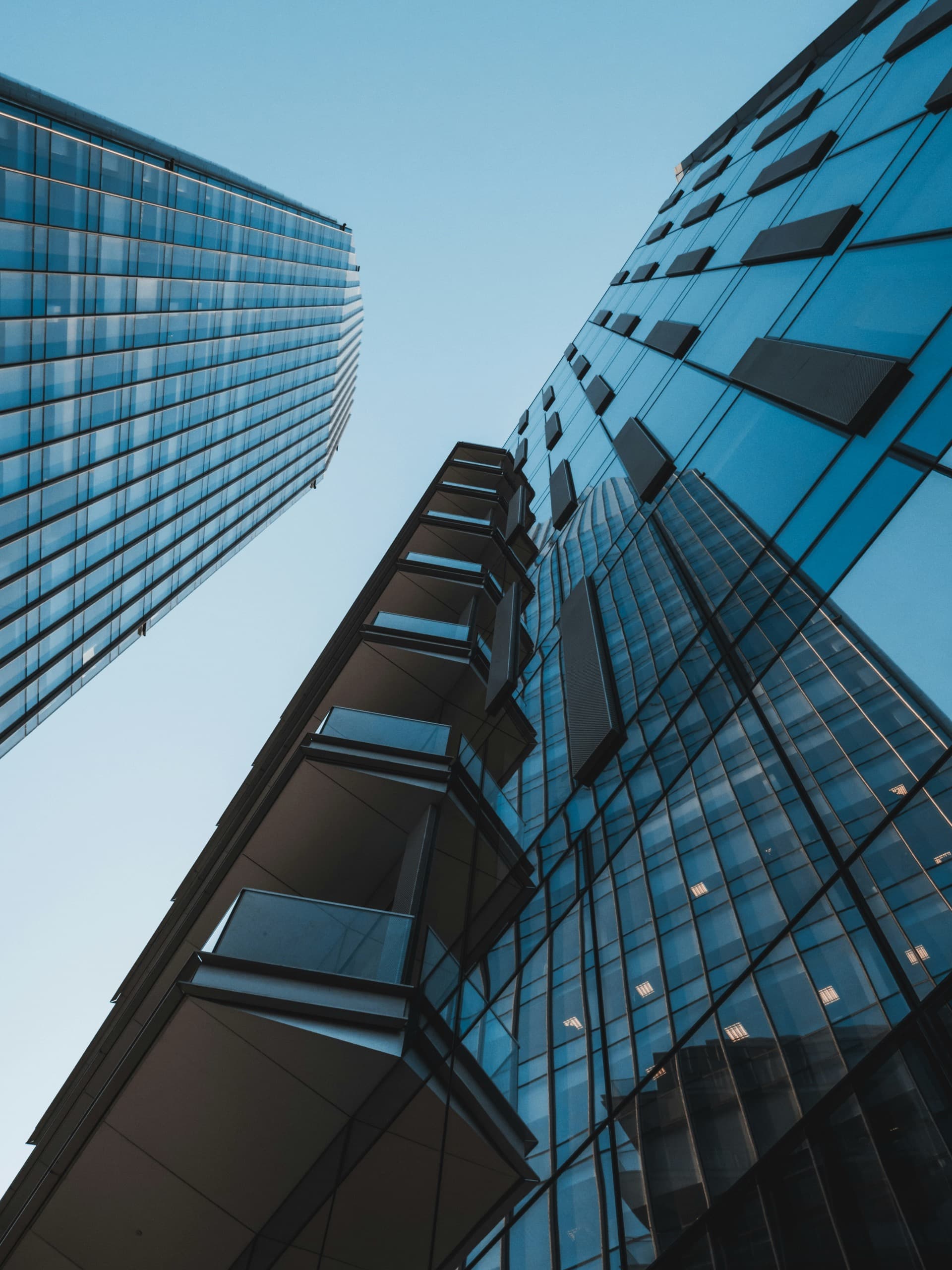 Looking up at glass office towers against a clear sky