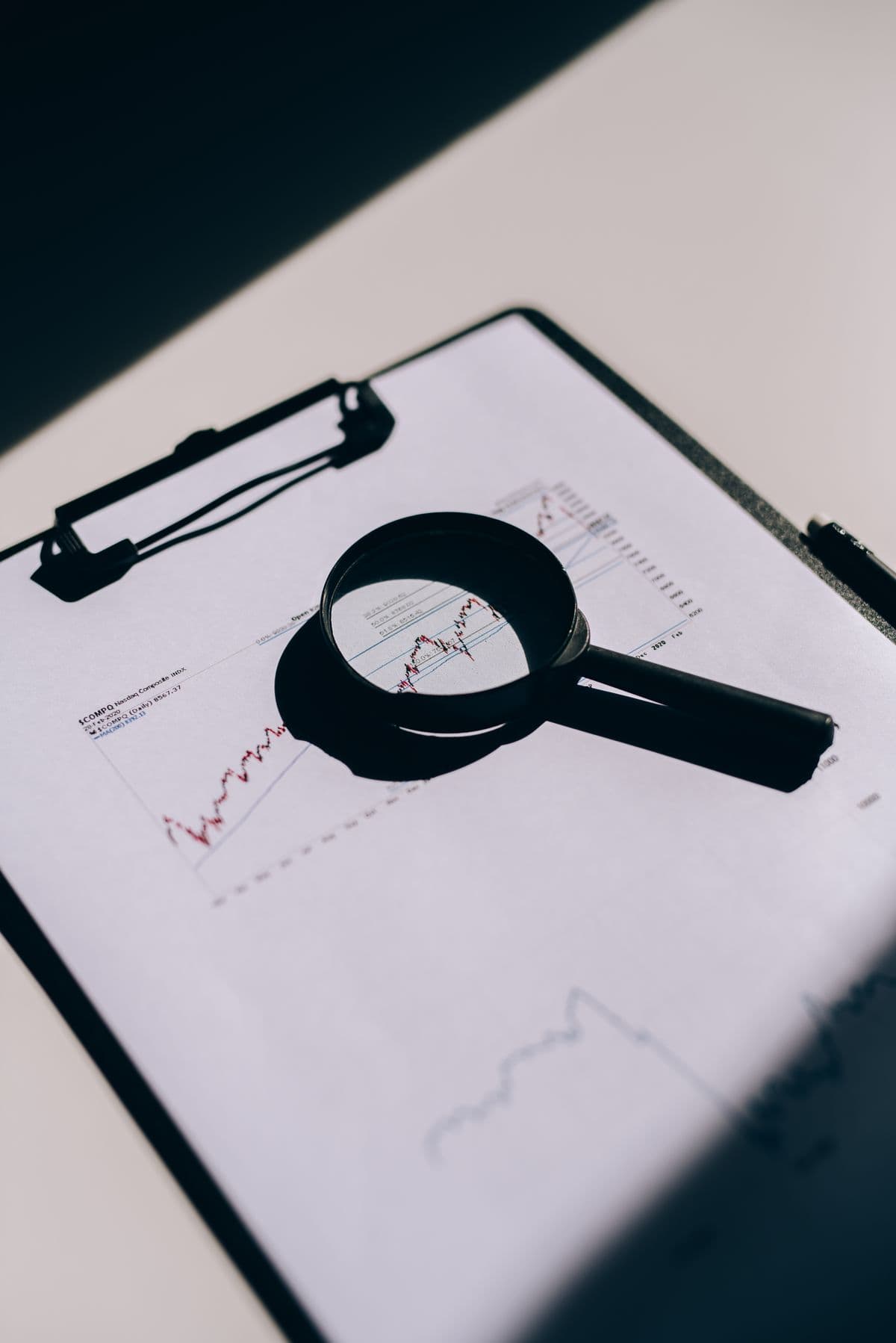 Magnifying glass over a printed financial performance chart