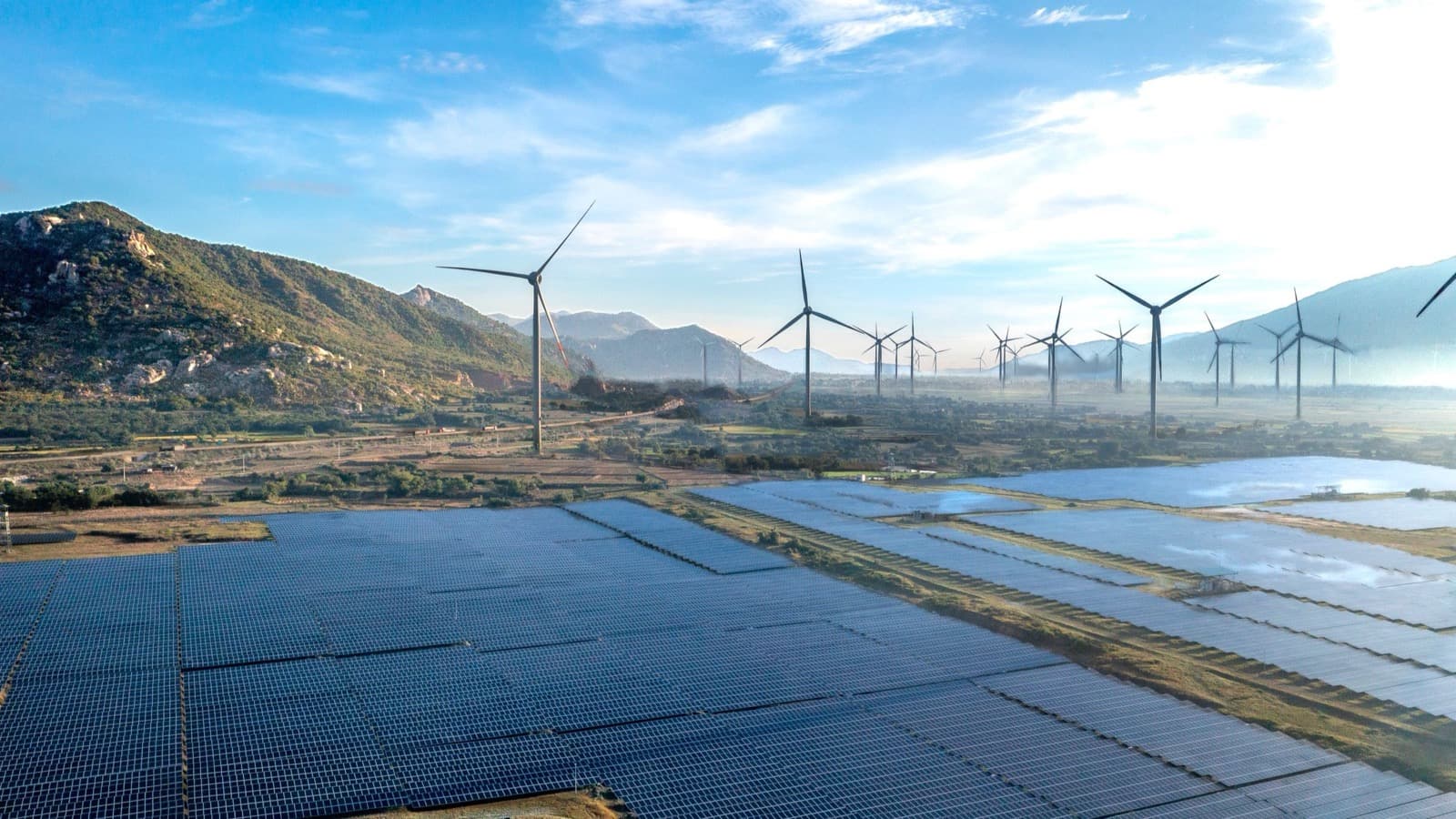 Aerial view of a wind farm and solar modules at sunrise